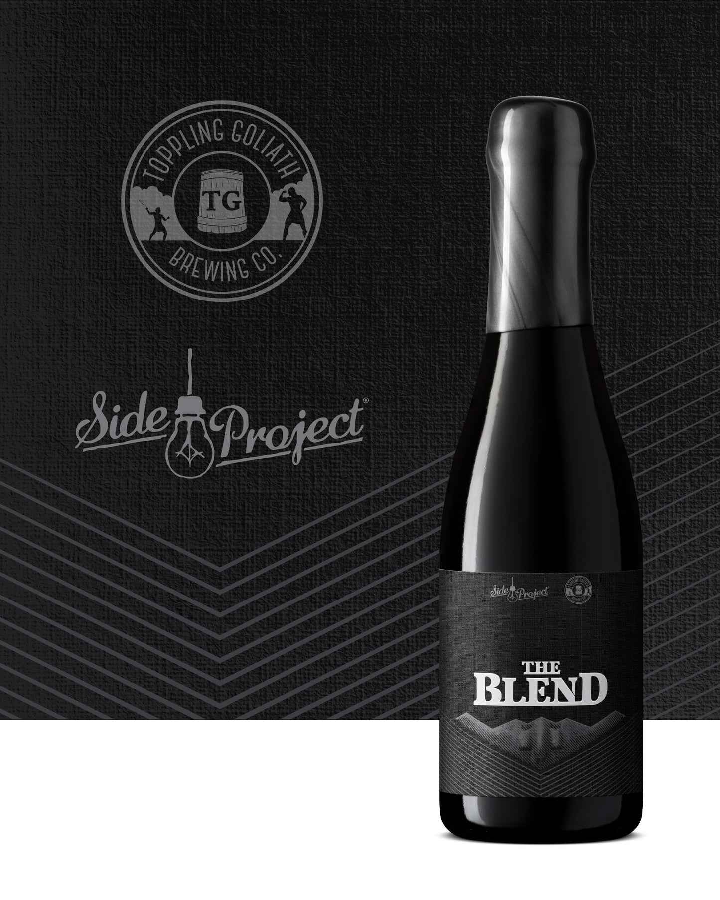 Black beer bottle labeled 'The Blend' with Topping Goliath Brewing Co. and Side Project logos on a dark background.