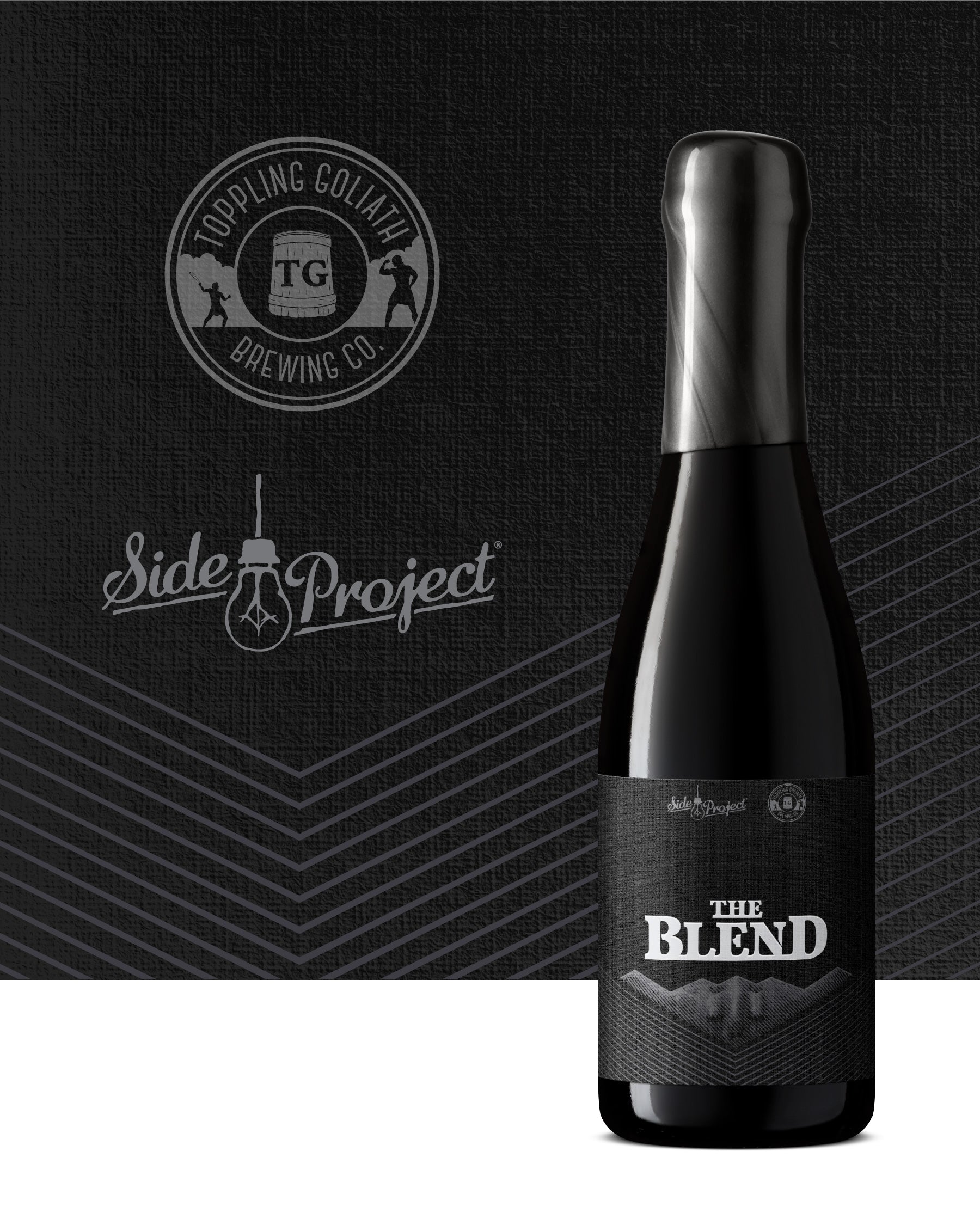 Black beer bottle labeled 'The Blend' with Topping Goliath Brewing Co. and Side Project logos on a dark background.