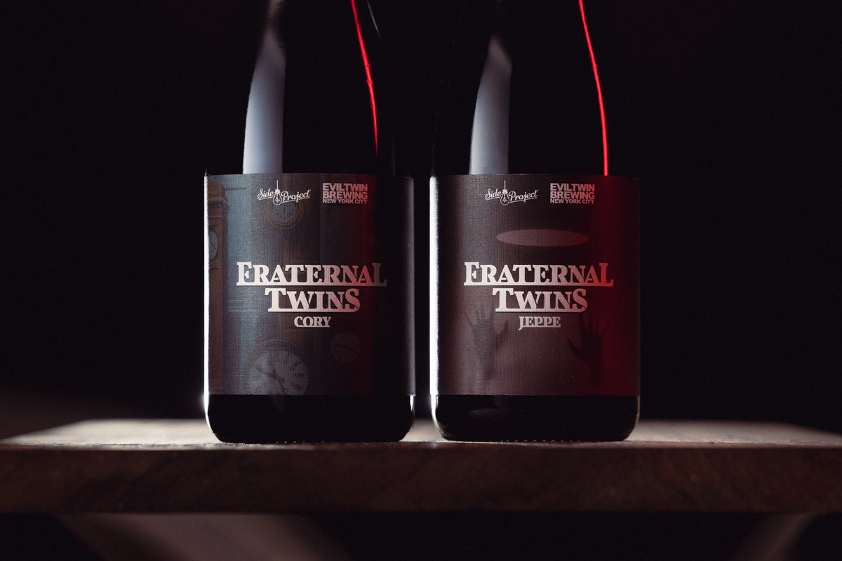 Two bottles of Marble Lions Barrel Aged Imperial Stout Beer with a gold medal in front of whiskey barrels.